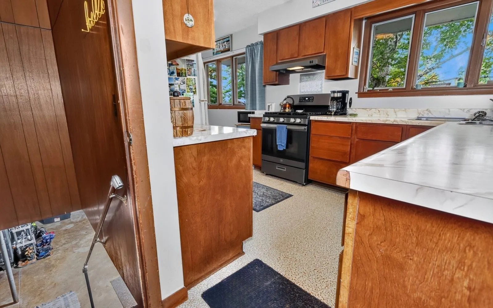 Living room with wood paneling, a wood stove, and windows toward the kitchen